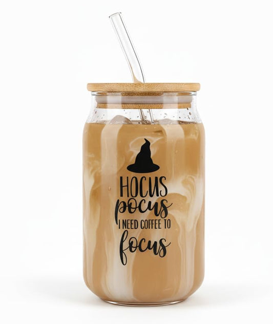 Glass jar with wooden lid and straw, filled with a coffee-like liquid, on a white background.