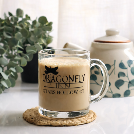 Glass mug with 'Dragonfly Inn Stars Hollow, CT' on a coaster with a blurred background