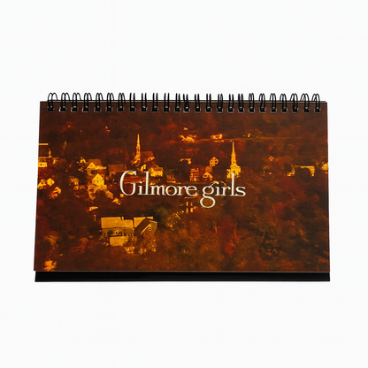 Notebook with 'Gilmore Girls' title on a cityscape background