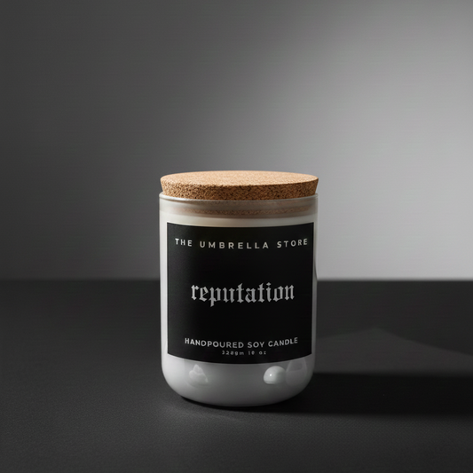 Candle jar with cork lid labeled 'reputation' from 'The Umbrella Store' on a dark background